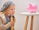 Little girl looking at piggy bank