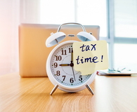 A clock with tax time sticky note