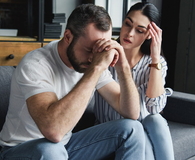 Depressed young couple sitting on couch at home
