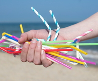 Hand Holding Plastic Straws Polluting Beach
