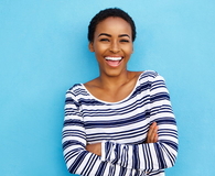 Happy young woman laughing against blue wall