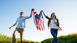 Couple holding amrican flag and running in field